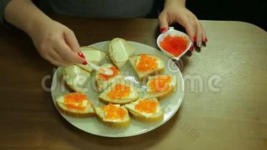一个女人从一勺鱼子酱中取出红色的鱼子酱，用黄油涂在罐头上
